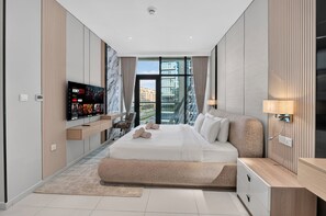 Ein modernes Hotelzimmer mit einem großen Bett, einem an der Wand befestigten Fernseher und Blick auf die Stadt durch große Fenster.