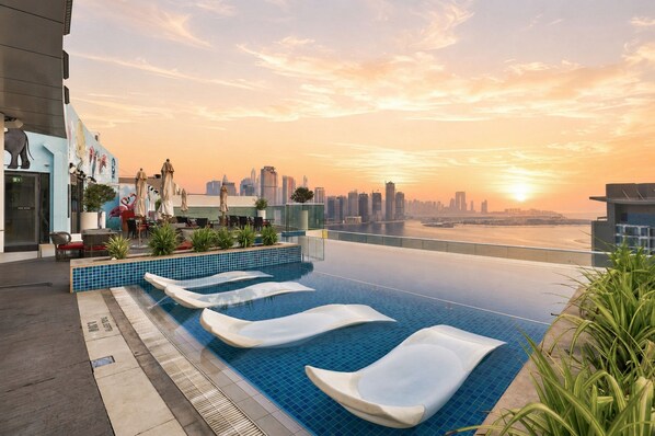 Ein Pool ohne Ende mit Blick auf eine städtische Skyline bei Sonnenuntergang.