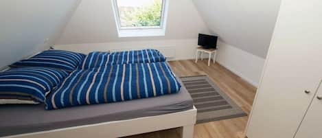 A bedroom with a bed, a television on a small table, and a wardrobe.