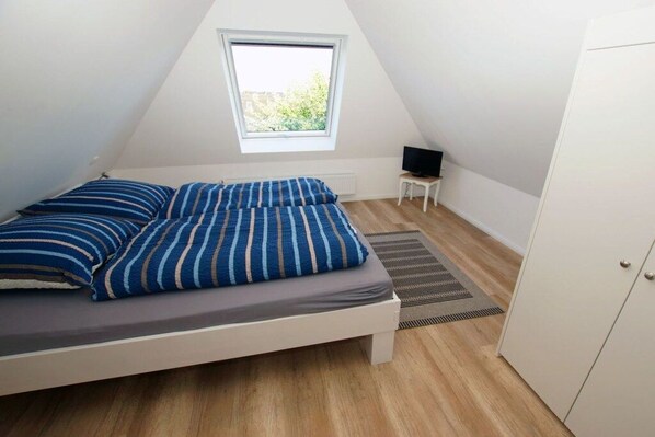 A bedroom with a bed, a television on a small table, and a wardrobe. - Apartment 4 in the Mare Cimbria building (Norddorf auf Amrum)