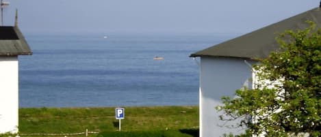 A coastal view with a parking sign, a building, and the sea.