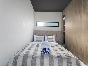 Ein Schlafzimmer mit Bett, Kleiderschrank und Fenster.