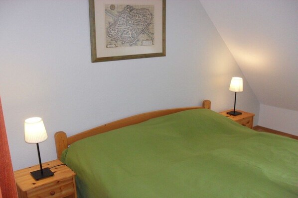 A bedroom with a single bed, two bedside tables, and a framed map on the wall. - Holiday home with 2 bedrooms (Breege-Juliusruh)