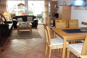 A living room with a sofa, coffee table, and dining area with chairs and a table. - Holiday home with 2 bedrooms (Breege-Juliusruh)