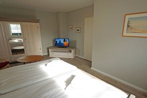 A bedroom with a bed, a television, a wardrobe, and a small table. - Holiday home in Prerow with barbecue (Prerow)