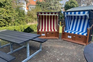 Two striped beach chairs with attached storage compartments, a picnic table, and a small round table. - Holiday home in Prerow with barbecue (Prerow)
