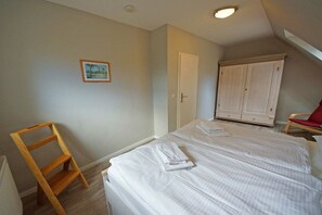 A bedroom with a bed, a wooden ladder, a wardrobe, and a door. - Holiday home in Prerow with barbecue (Prerow)