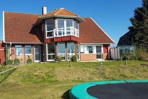 A two-story house with a balcony, a swimming pool, and a well-maintained lawn. - Holiday apartment in Hohwacht with barbecue (Hohwacht)