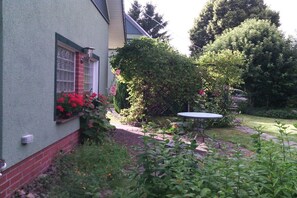 A house with a garden, a brick wall, a window with a red frame, and a table in the yard. - Holiday home in Daschow with swimming pool (Daschow)
