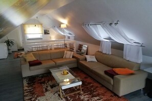 Un salon moderne avec un canapé d’angle, une table basse en verre et un tapis à motifs.
