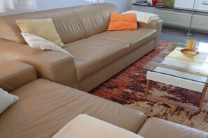 A beige sofa with cushions, a glass coffee table, and a patterned rug. - Holiday home in Daschow with swimming pool (Daschow)