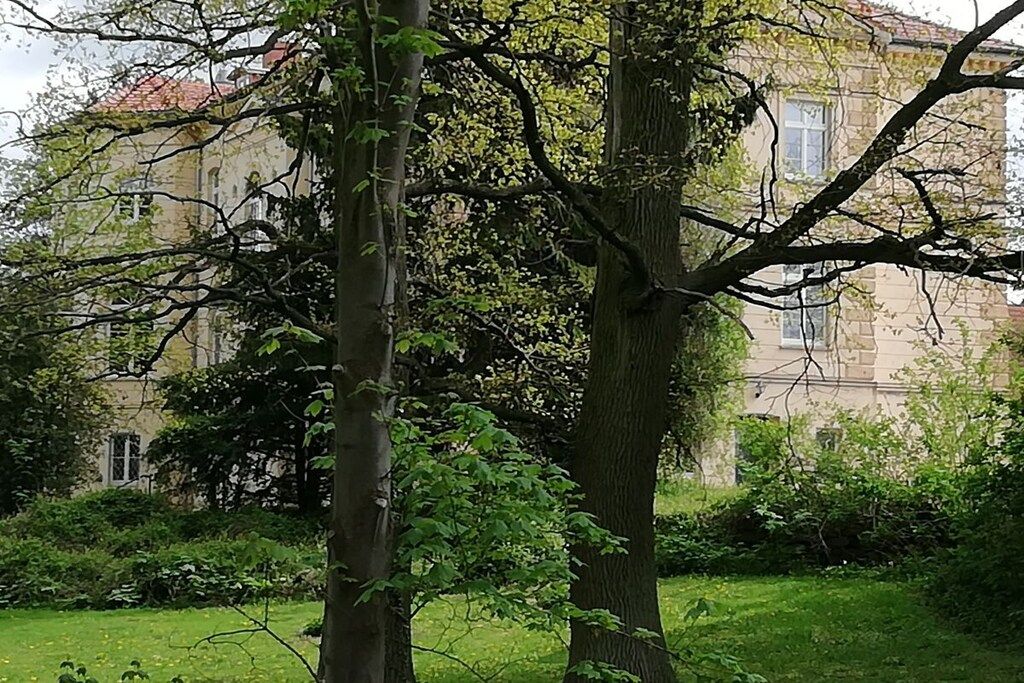 A building with a classical architectural style, surrounded by a well-maintained garden with mature trees.