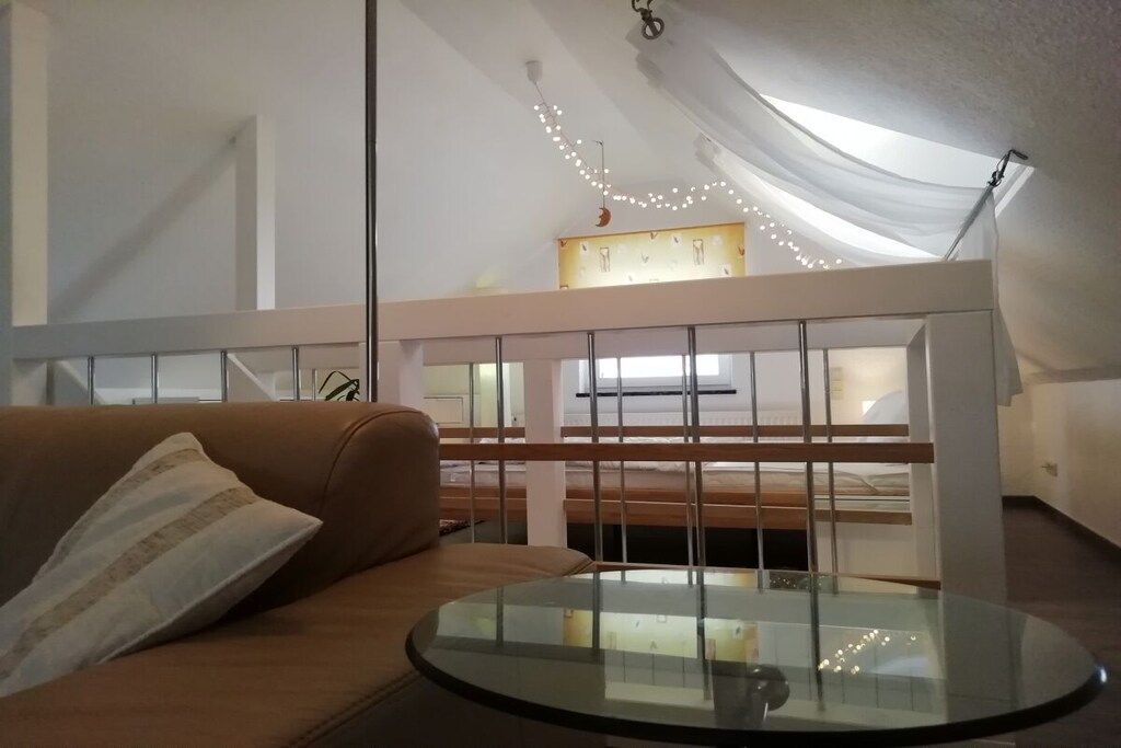 A room with a glass-top table, a brown sofa, and a white railing.