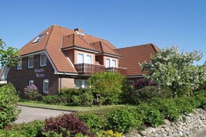 A two-story house with a brick facade, a sloped roof, and a balcony. - Holiday apartment in Büsum with swimming pool (Büsum)