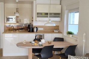 A modern kitchen with a dining area, featuring a microwave, kettle, and a table set for two. - Hesse "Bi"d Achterdör" (Langeoog)