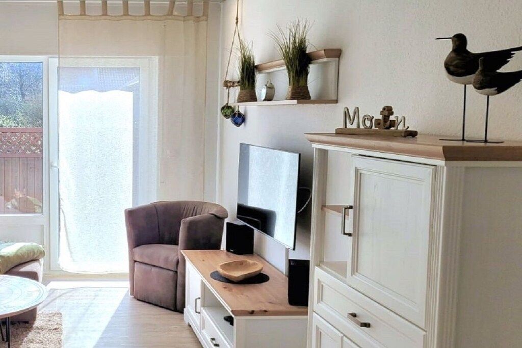 A living room with a sofa, a TV, a wooden side table, and a cabinet.