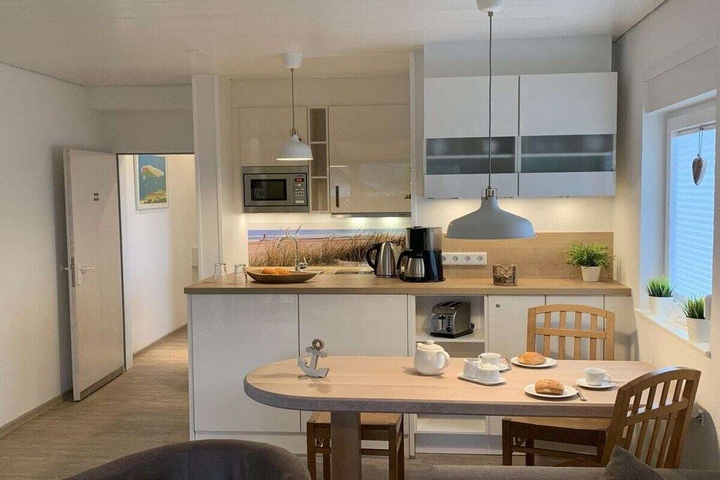 A modern kitchen with a central island, a dining table, and a microwave.