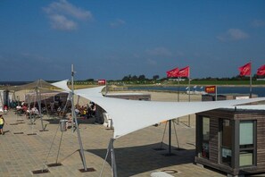 An outdoor seating area with tables and chairs, a small kiosk, and a tent structure. - Dat Fischerhus - Ground Floor (Büsum)