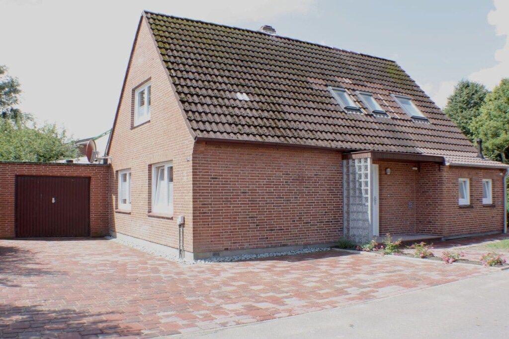 A single-story brick building with a sloped roof, a garage door, and a small porch area.