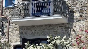 Un bâtiment en pierre doté d’un balcon, d’un auvent bleu et d’une antenne parabolique.