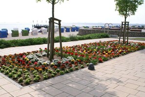 A landscaped area with a flower bed, seating, and a view of the sea. - in the Seeadler building at number 9 (Wyk)