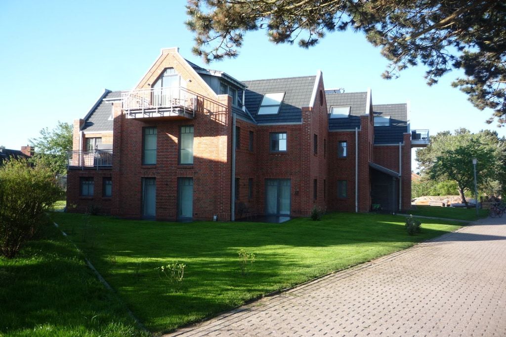 A two-story brick building with a flat roof, a balcony on the upper floor, and a paved driveway.