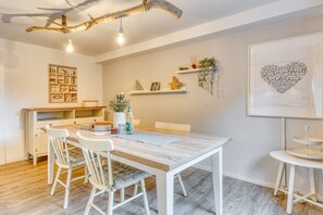 A dining area with a wooden table, white chairs, and a ceiling light fixture. - Holiday apartment with 2 bedrooms (Norderney)