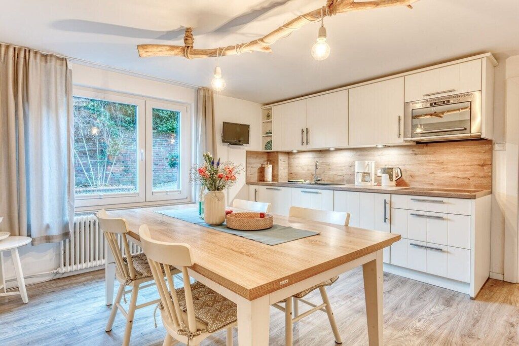Een moderne keuken met witte kasten, een houten aanrecht en een inbouwoven.