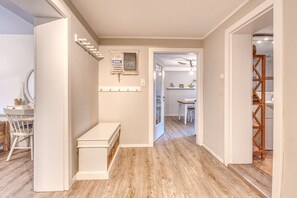 A hallway with a bench, a wall-mounted shelf, and a door leading to a dining area. - Holiday apartment with 2 bedrooms (Norderney)