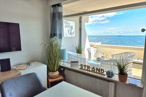 A room with a view of the sea, a desk with a computer, a chair, and a sign that reads 'STRAND'. - Holiday apartment with 2 bedrooms (Sierksdorf)
