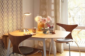 A dining area with a table, chairs, a vase with flowers, and a lamp.