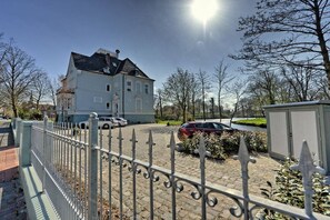 Une propriété résidentielle avec une allée pavée, une clôture blanche et une voiture garée.