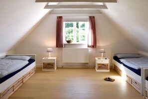 A dormitory room with two beds, a window with curtains, and a small table with a lamp. - Old Shoemaker's House (Stenderup bei Gelting)