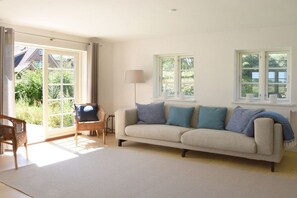 A living room with a sofa, two chairs, a lamp, and a large window. - Old Shoemaker's House (Stenderup bei Gelting)