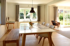 A dining area with a wooden table, chairs, a bench, and a hanging pendant light. - Old Shoemaker's House (Stenderup bei Gelting)