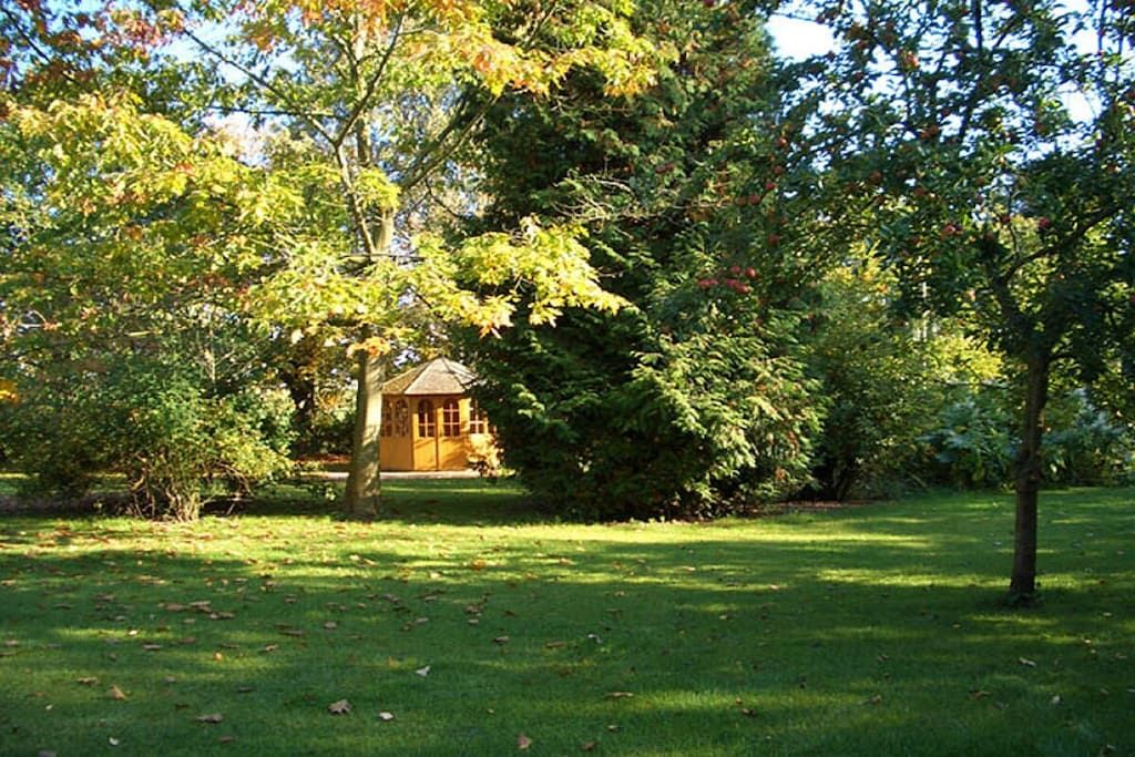A serene garden with a small building surrounded by trees and grass.