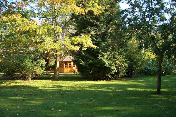 A serene garden with a small building surrounded by trees and grass. - "Sun-filled apartment on the Schlei" (Akeby)