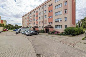 Ein mehrgeschossiges Wohngebäude mit Parkplatz davor.