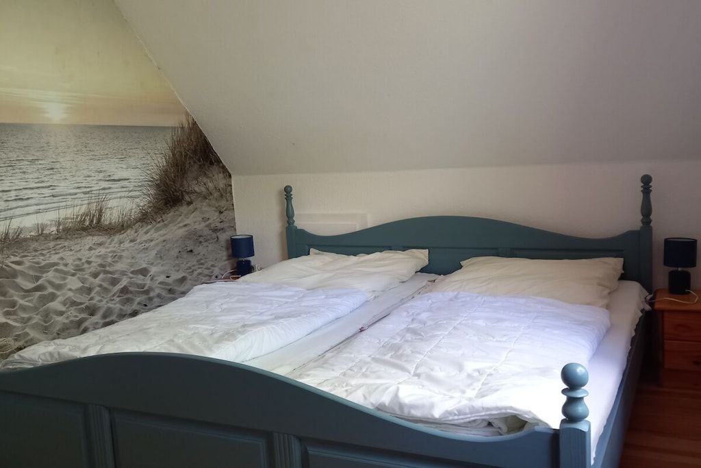 A bed with a headboard, two bedside tables, and a view of the beach.