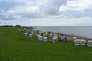 A coastal area with numbered tents on a grassy field, a beach, and a body of water. - Holiday apartment with 3 bedrooms (Dagebüll-Hafen)