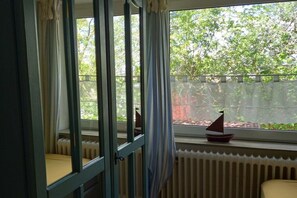 Ein Zimmer mit Fenster, Heizkörper und einem kleinen Segelbootmodellbrett.