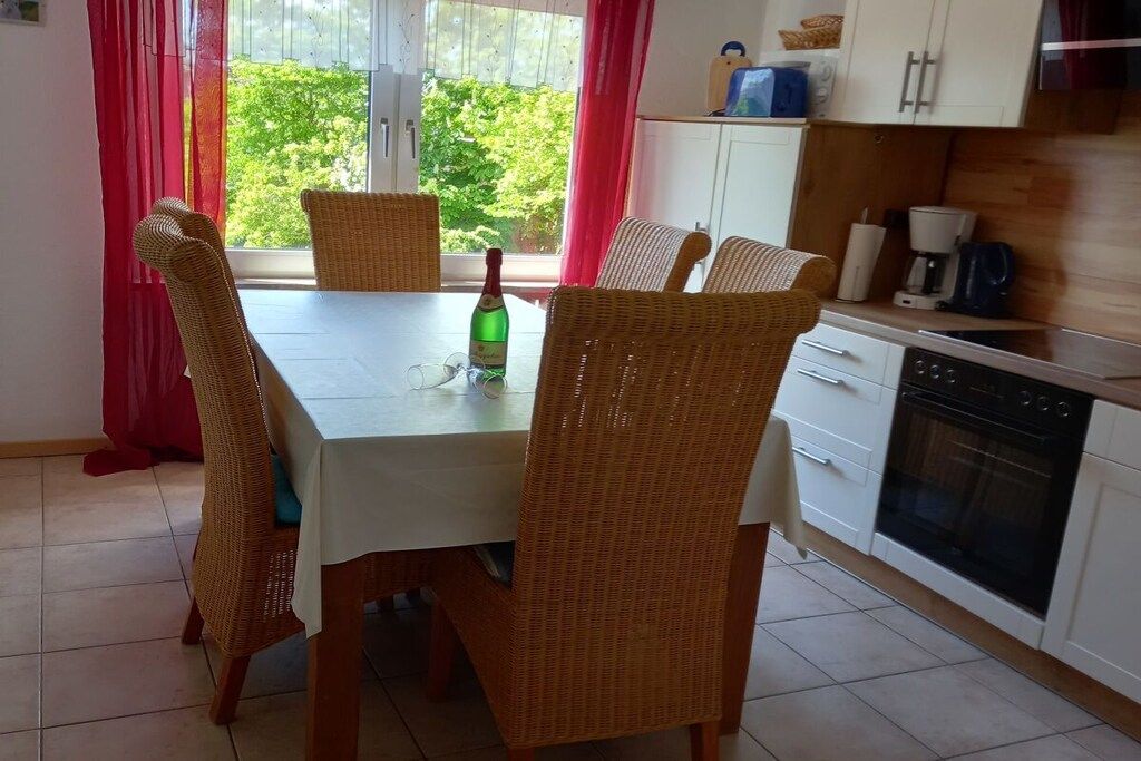 En matplats med ett bord och stolar, en flaska och utsikt över grönområden utanför.