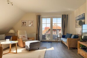 Ein gemütliches Wohnzimmer mit einer Couch, einem Sessel und einem Fernseher.