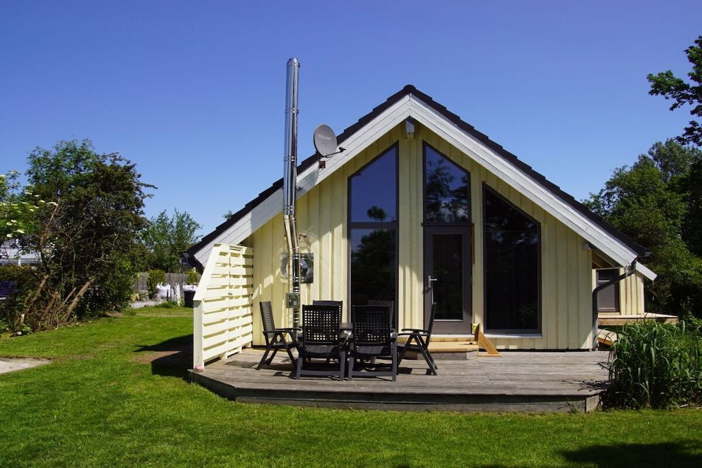 A small, single-story building with a sloped roof, a satellite dish, and a patio with outdoor furniture.