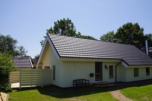 A single-story building with a gabled roof, a front porch, and a small attached garage. - Holiday home with 2 bedrooms (Schönberger Strand)