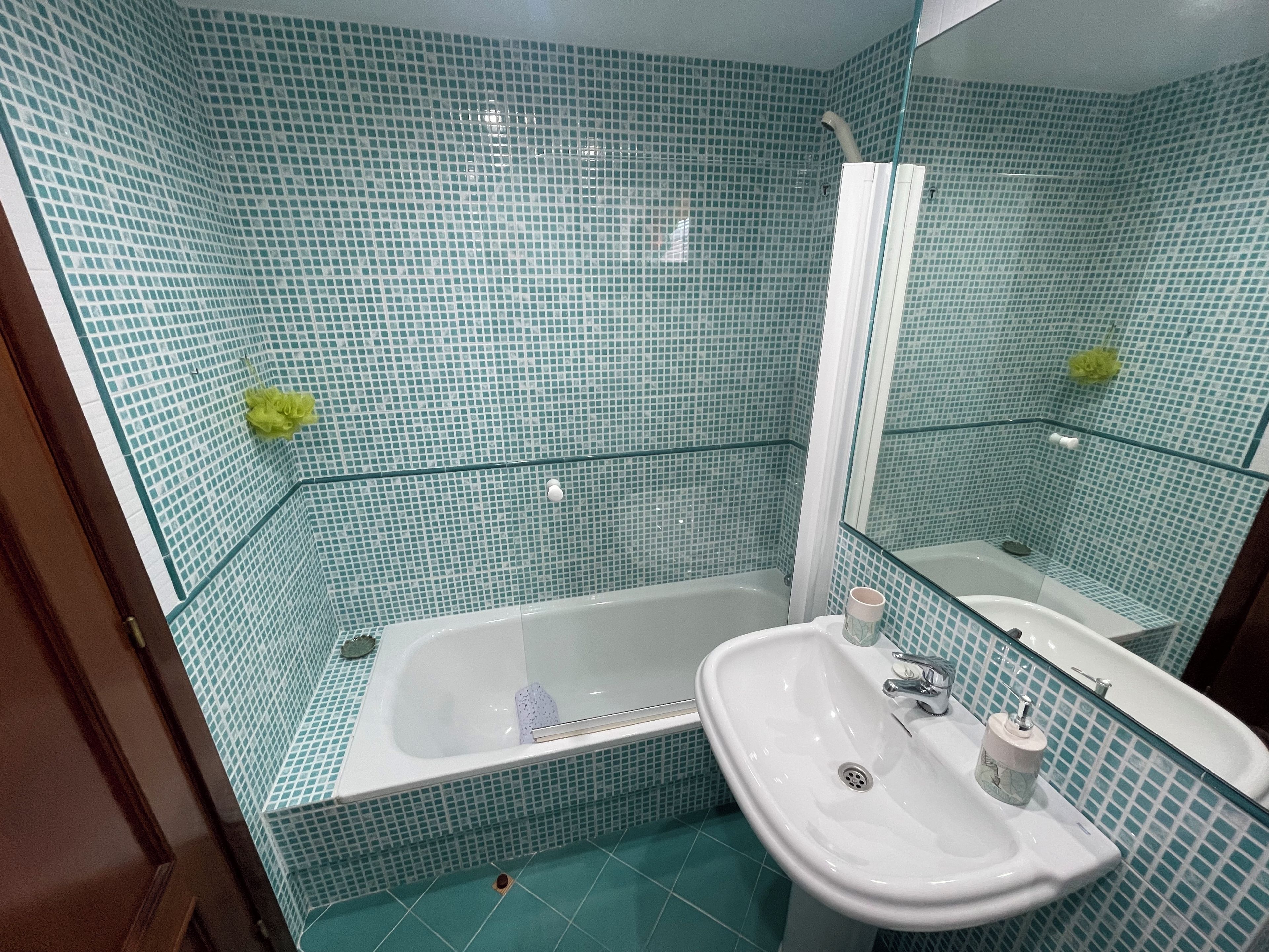 Een badkamer met een bad, wastafel en spiegel.