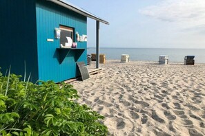 A beachside shack with a small porch and a signboard, surrounded by sand and a clear sky. - Holiday home in Hohwacht with swimming pool (Hohwacht)