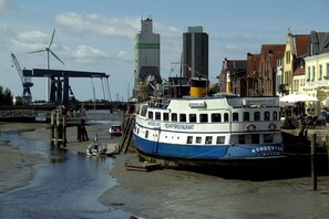 A boat docked at a pier with a cityscape in the background. - Holiday apartment with 1 bedroom (Ahrenviöl)