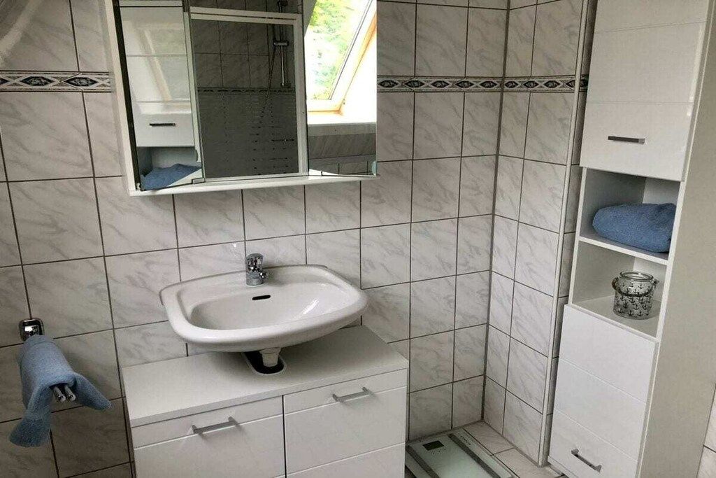 A bathroom with a white sink, a mirror, and a towel rack.
