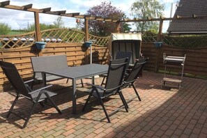 An outdoor patio with a table and chairs, a barbecue grill, and a wooden fence. - Holiday home in Esgrus with swimming pool (Esgrus)